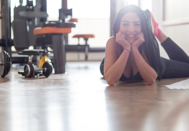 Beautiful young woman sitting down and relaxing at a gym - Fotoğraf, Görsel