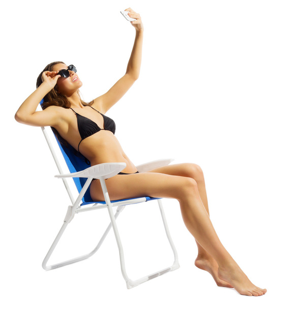 Young girl in swimsuite on chair with mobile phone - Fotó, kép