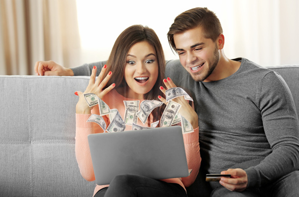 Οικονομική έννοια. Κερδίστε χρήματα στο διαδίκτυο. Νεαρό ζευγάρι ευτυχισμένο με φορητό υπολογιστή στο σπίτι - Φωτογραφία, εικόνα