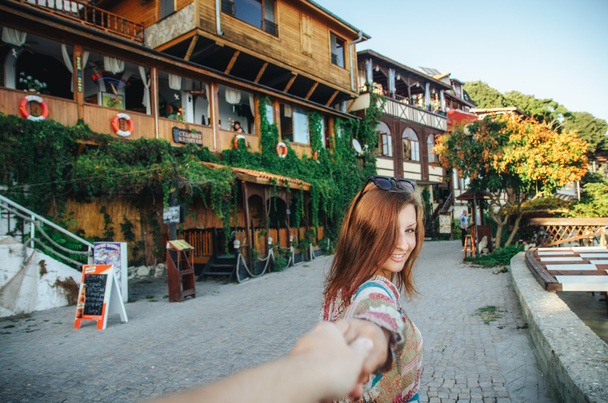 Mädchen führt zu Fuß entlang der Straße mit alten Holzgebäuden in der Altstadt von Nessebar - Foto, Bild