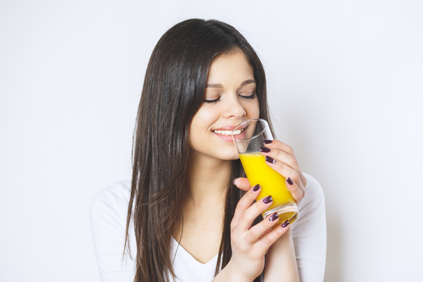 Portret van aantrekkelijke Kaukasische Glimlachende vrouw geïsoleerd op witte Studio schot drinken sinaasappelsap gezicht huid. Portret van een mooie vrouw die glas met smakelijk SAP vasthoudt . - Foto, afbeelding