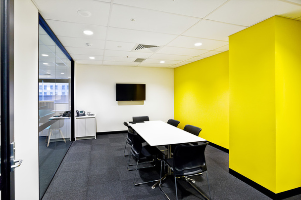Pequeña sala de reuniones con paredes amarillas y tv
  - Foto, imagen