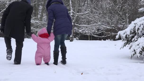 Bambino che impara a camminare. Padre con madre insegnare neonata al parco invernale. 4K
 - Filmati, video