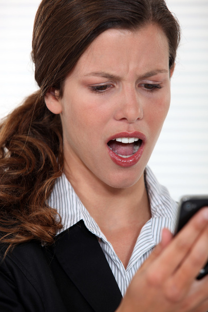 Woman staring in disbelief at her mobile phone - Photo, image