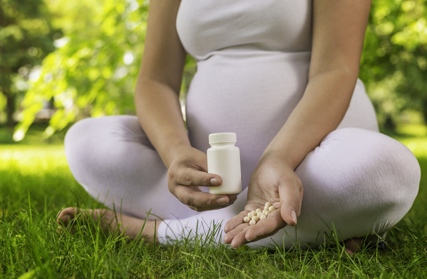Mulher grávida segurando pílulas
 - Foto, Imagem