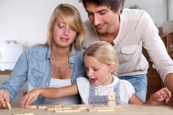 Pareja feliz jugando dominó con hija
 - Foto, imagen