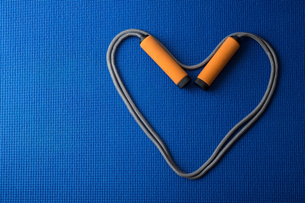 Kalp mavi yoga mat arka plan üzerinde ip atlama üzerinden - Fotoğraf, Görsel