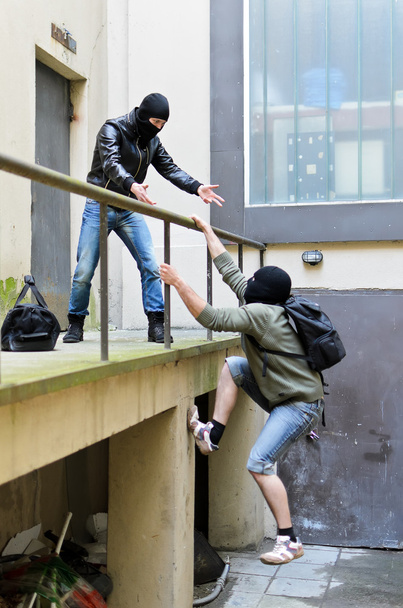 Escape from a robbery. One tries to help another to climb the rails. - Foto, Imagem