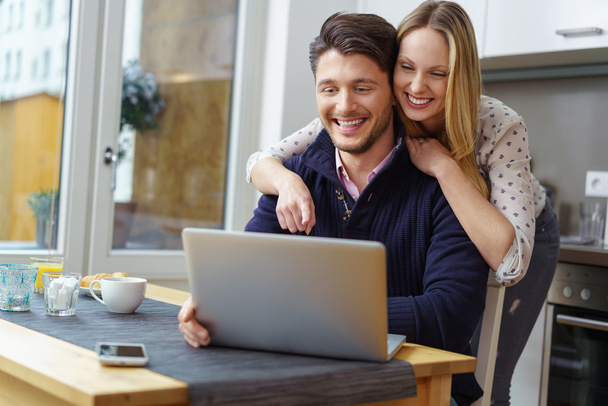 Laughing woman leaning on happy man using laptop - 写真・画像
