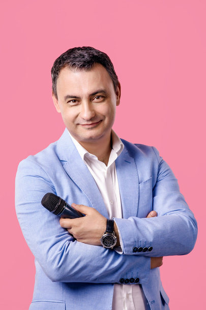 Portrait of middle aged man with microphone in hand wearing blue jacket. smiling. isolated pink background. - Foto, Imagem