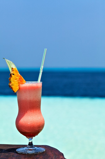 Copo de bebida está em uma mesa de praia
 - Foto, Imagem