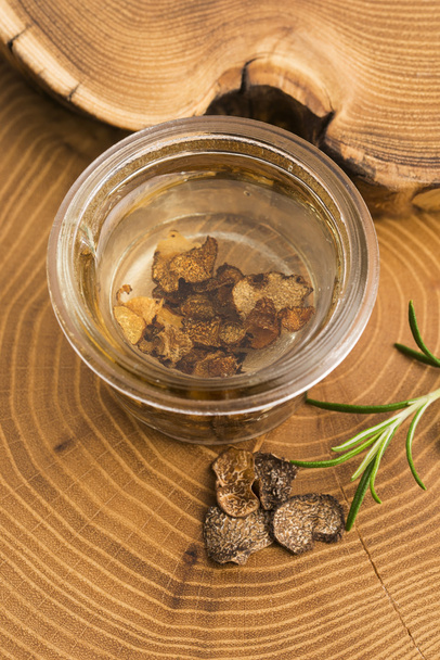 Zwarte truffel in olijfolie in de kleine pot en verse rosemar gesneden - Foto, afbeelding