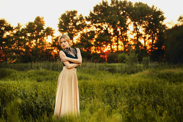 módní fotografie krásná mladá dívka s plavými vlasy, nosí luxusní béžové šaty na západ slunce. - Fotografie, Obrázek