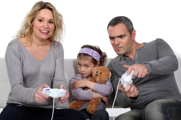 Man and woman playing to video games with little girl pouting - Foto, imagen