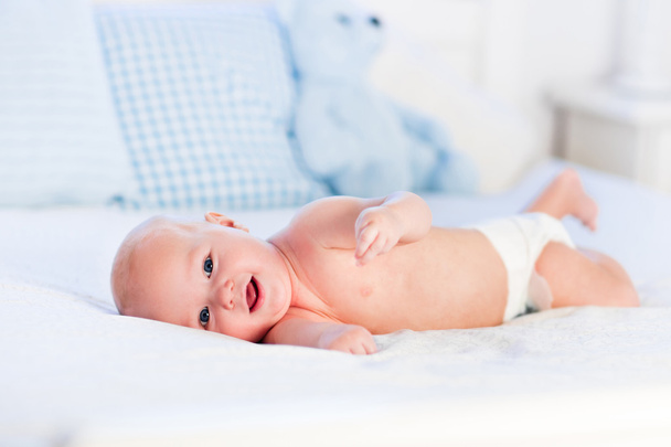 babyjongen op witte bed - Foto, afbeelding