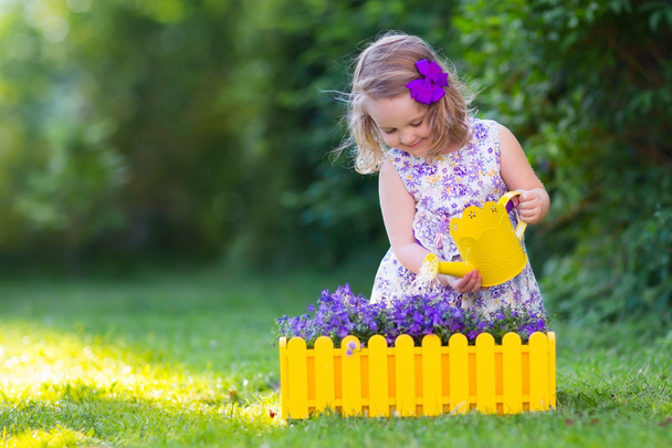 Маленька дівчинка поливає квіти садівника
 - Фото, зображення
