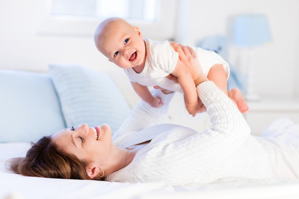 Mother and baby on a white bed - Foto, Imagen