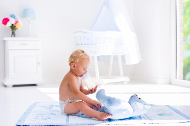 Bebé niño con biberón de leche en el vivero soleado
 - Foto, Imagen