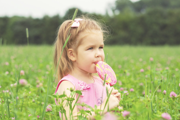  Klein meisje eet een lolly - Foto, afbeelding