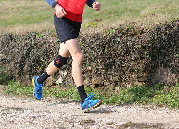corredor durante la carrera a campo traviesa con la rodilla envuelta por una rodilla
 - Foto, Imagen