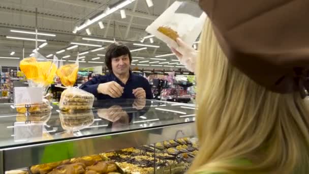 Sütőipari munkás egy sütemény, egy ügyfél átadja a számláló értékesítés - Felvétel, videó