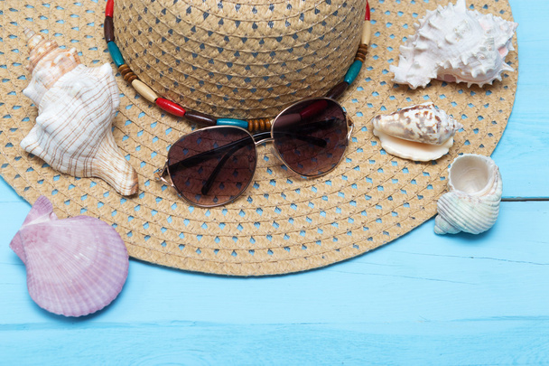 Seashells, chapéu e óculos de sol em fundo de madeira azul
 - Foto, Imagem