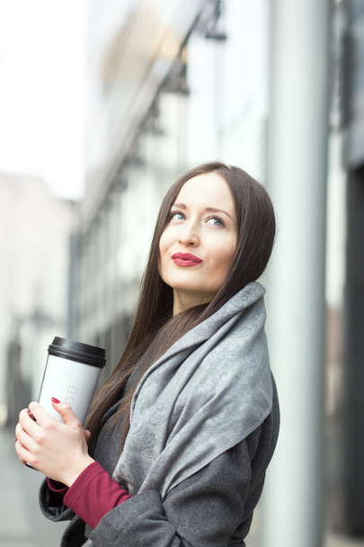 Mulher morena atraente desfrutando de café perto do centro de negócios
 - Foto, Imagem