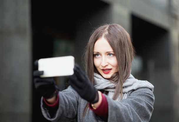 Portrait of attractive woman doing selfie outdoors in city - Фото, изображение