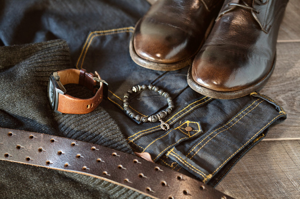 mannen casual mode kleding en accessoires - jeans en riem, leren schoenen, pols horloge, armband aan kant - Foto, afbeelding