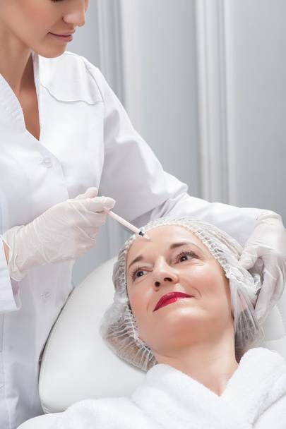 Cheerful expert beautician is serving her patient - Photo, image