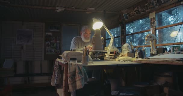 Old artist models a clay sculpture in a small studio - Footage, Video