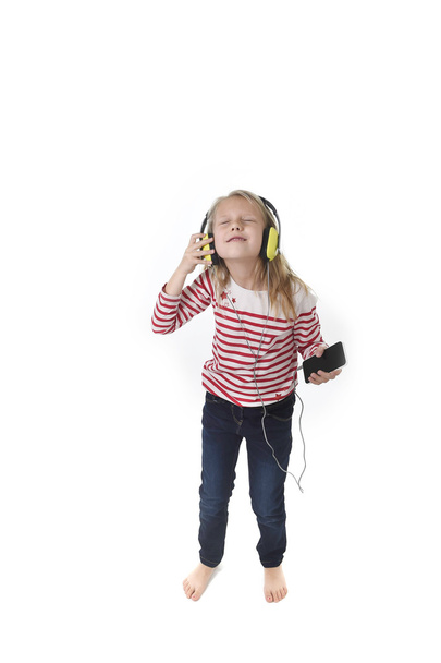 słodkie dziewczynki z blond włosami słuchanie muzyki z słuchawek i telefonu komórkowego śpiew i taniec szczęśliwy - Zdjęcie, obraz