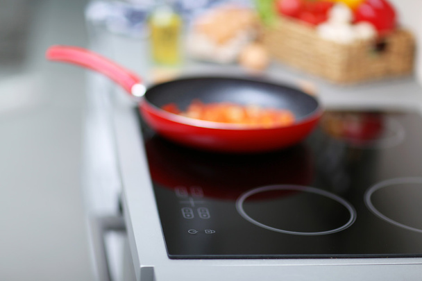 Frying pan on stove with pepper and mushrooms, closeup - Fotó, kép