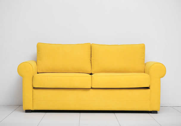 Yellow sofa against wall  - Фото, зображення