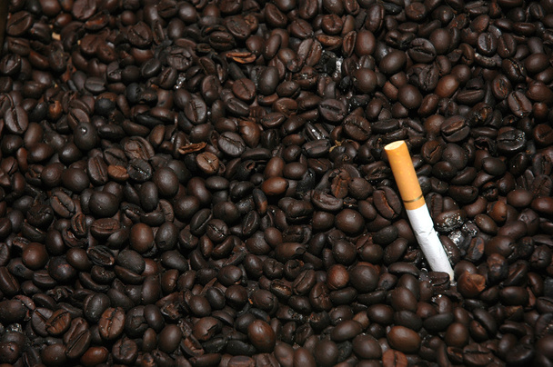 Сигаретні сідниці на купі смажених кавових зерен використовуються як попільничка
 - Фото, зображення