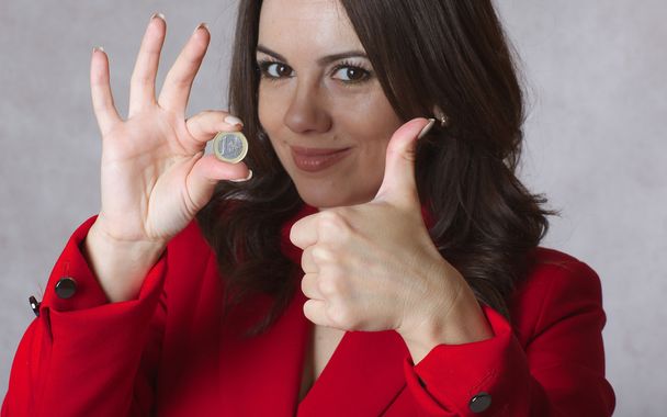 One euro coin in the hand of a young woman. - Фото, изображение