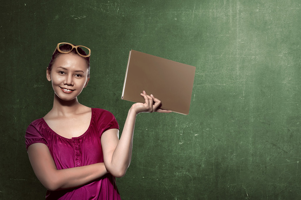 female student holding book with chalkboard background - Foto, immagini