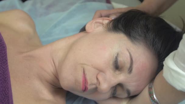 Masseuse fazem a massagem remedial da cabeça à mulher jovem no salão profissional
. - Filmagem, Vídeo