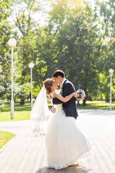 wedding couple hugging, the bride holding a bouquet of flowers,  groom embracing her - Foto, Bild