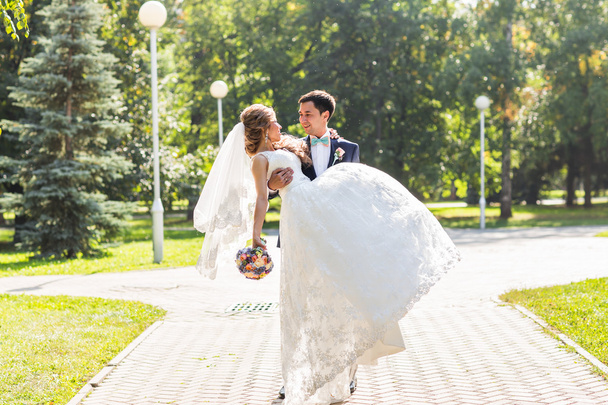 onu kucaklayan Düğün çifti, sarılma bir buket çiçek, holding gelin damat - Fotoğraf, Görsel