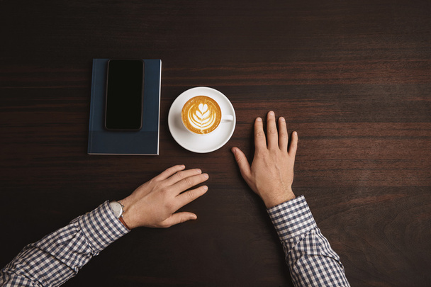 In center businessman hands near cup of cappuccino  - Φωτογραφία, εικόνα