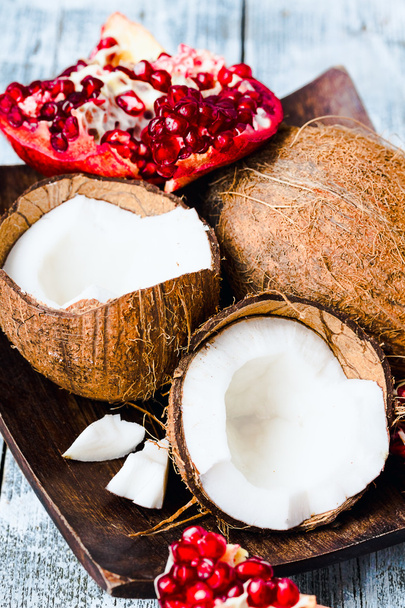 Fresh coconut and red garnet in a wooden bowl,blue background - 写真・画像