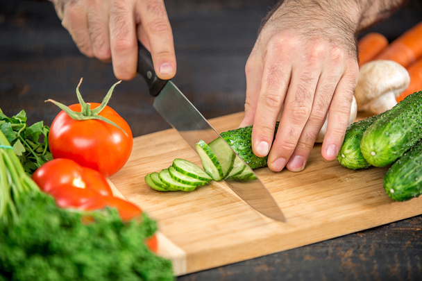 Male hands cutting vegetables for salad - Foto, afbeelding