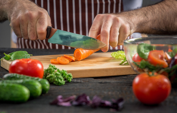 Чоловічі руки ріжуть овочі для салату
 - Фото, зображення