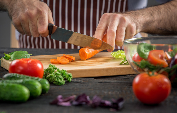 Mies kädet leikkaamalla vihanneksia salaattia
 - Valokuva, kuva