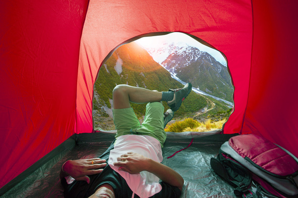 homem de acampamento deitado na barraca de acampamento ao ar livre com belo natural
 - Foto, Imagem