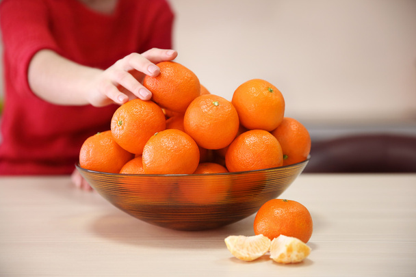 Woman taking tangerine from the bowl - 写真・画像