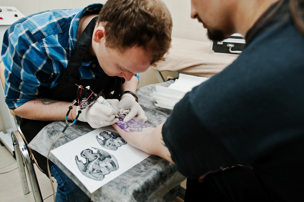 Tattoo master make tattoo for rocker man at tattoo salon - Photo, image