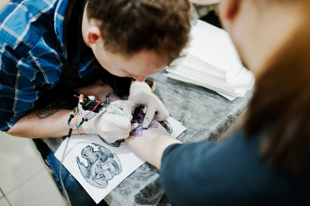 Tattoo master make tattoo for rocker man at tattoo salon - Photo, image