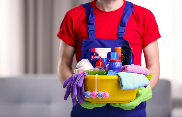 Man holding plastic basin with detergents indoors - Φωτογραφία, εικόνα